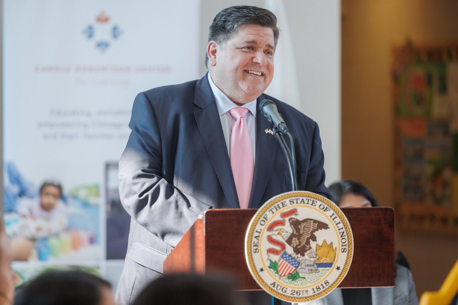 Governor J.B Pritzker speaking at podium smiling